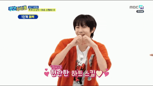 a young boy is making a heart shape with his hands on a mbc tv screen