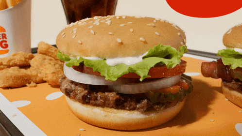 a burger king hamburger with lettuce tomato and onions on a table