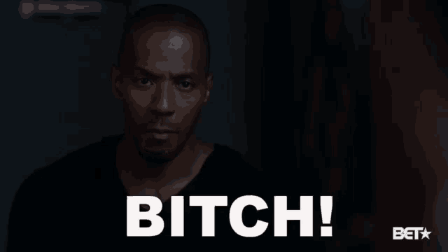 a man in a black shirt is standing in front of the word bitch