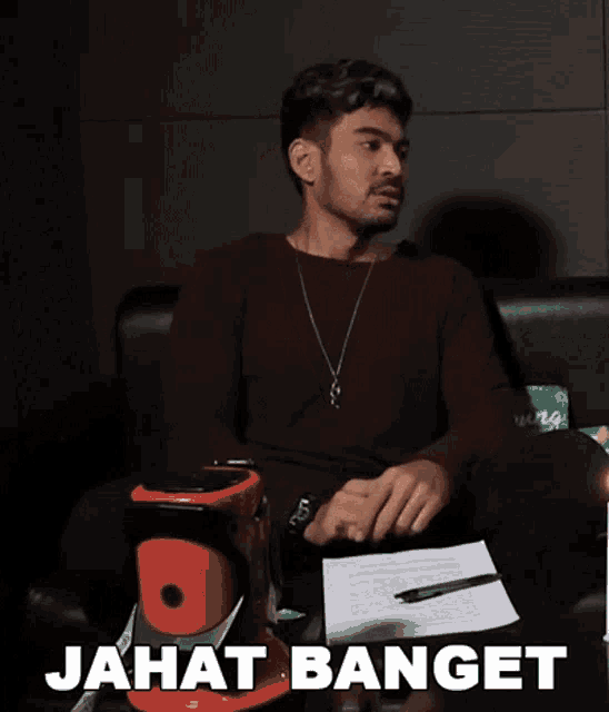 a man sitting on a couch with the words jahat banget written on the table