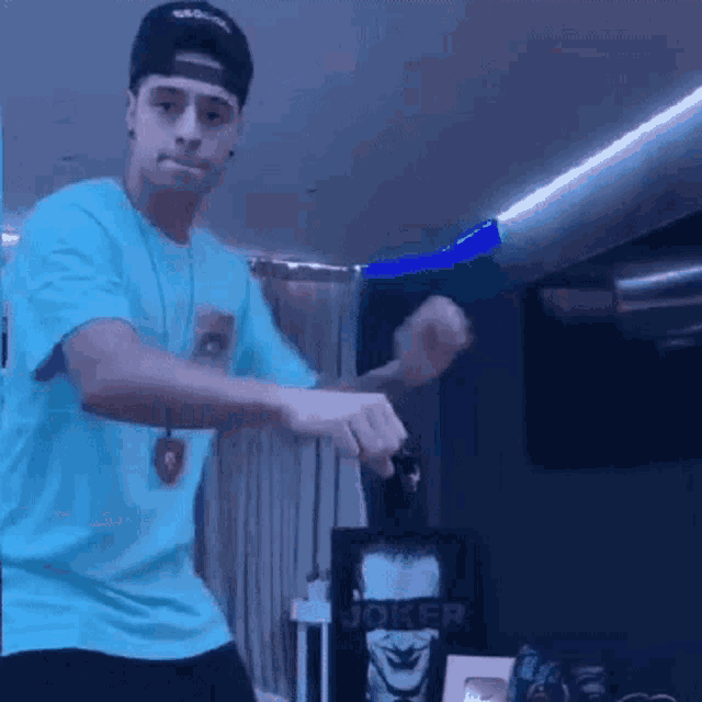a young man in a blue shirt and black hat is dancing in a room .