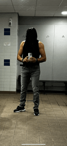 a man taking a picture of himself in a locker room with a sign that says no smoking
