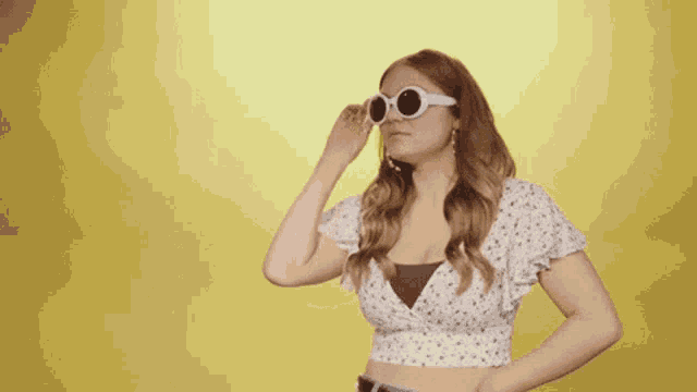 a woman wearing sunglasses and a crop top is making a face .