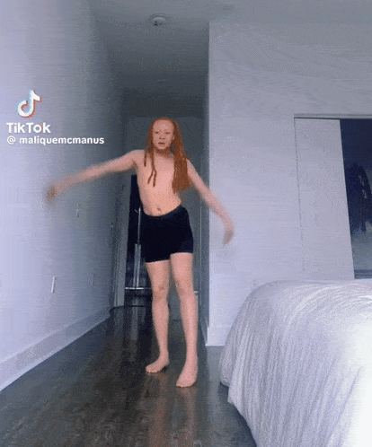 a young girl with red hair is dancing in a bedroom with a tiktok watermark