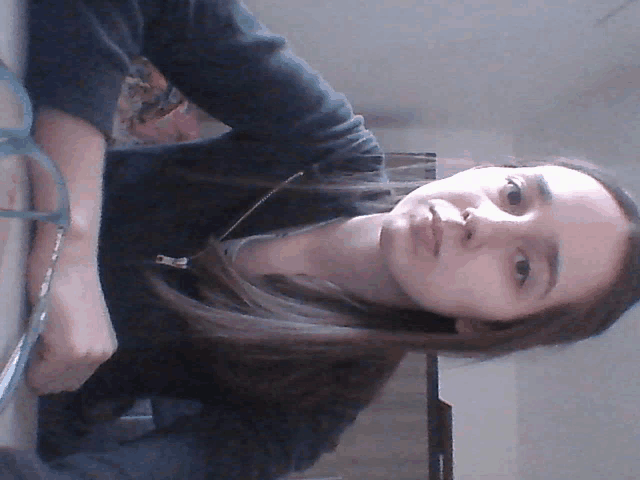 a woman wearing glasses and a black sweater looks at the camera