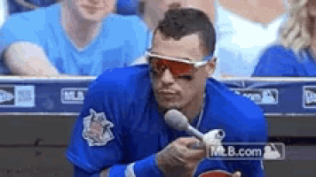 a baseball player wearing sunglasses and a blue shirt is holding a microphone in his hand .