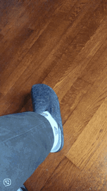 a person wearing a pair of crocs on a wood floor