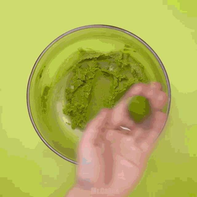 a person is mixing a green substance in a bowl that says mr.cakes