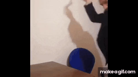 a man is throwing a blue bucket at a wall .