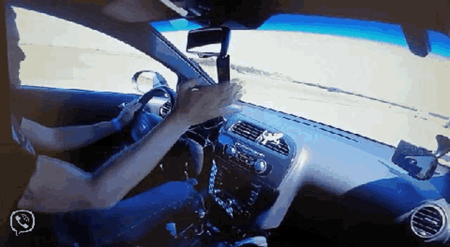 a man is driving a car with a phone on the dash