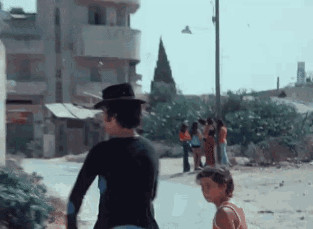 a man wearing a black hat is walking down a street