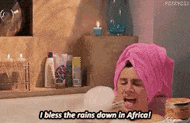 a man in a bathtub with a pink towel on his head says i bless the rains down in africa