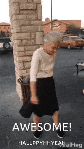 an elderly woman is standing in front of a brick wall and holding a hat .