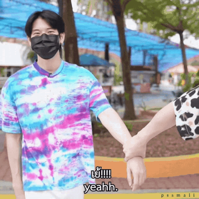 a man wearing a tie dye shirt holds another man 's hand and says " yeahh "
