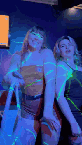 two women are standing next to each other in a dark room with blue lights .