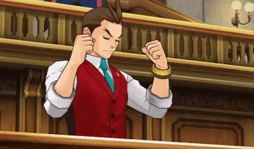 a man in a red vest and white shirt is standing in a courtroom with his fists in the air .