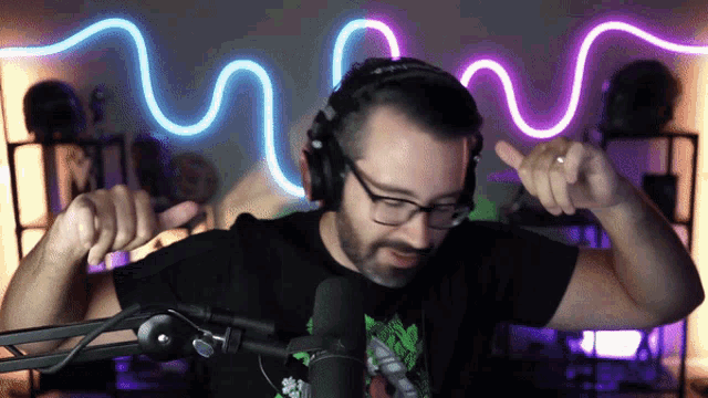 a man wearing headphones and glasses stands in front of a neon sign that says m
