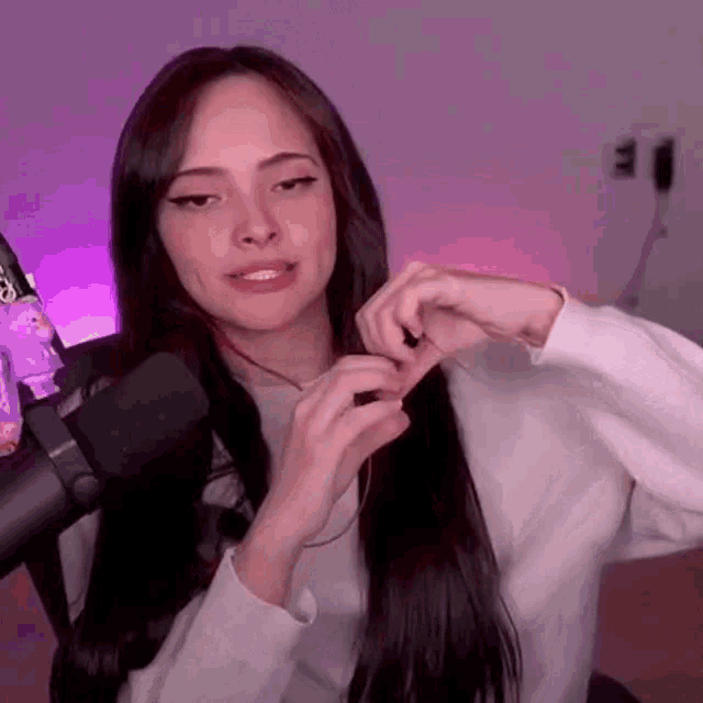 a woman is sitting in front of a microphone making a heart with her hands .