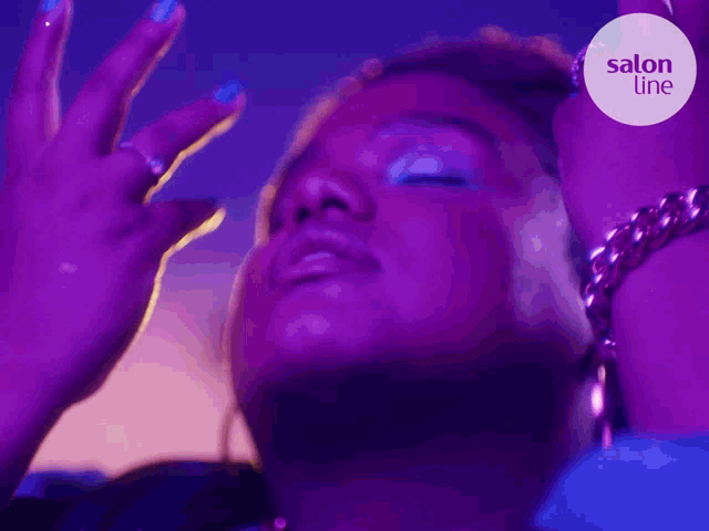 a woman 's face is shown in a purple light with salon line written in the corner