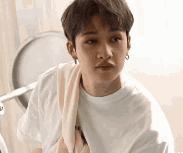 a young man with a towel around his neck is wearing a white t-shirt .