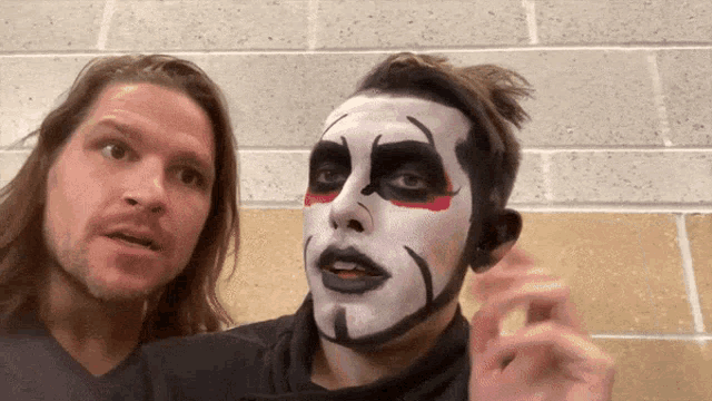 two men are standing next to each other with one wearing a clown makeup