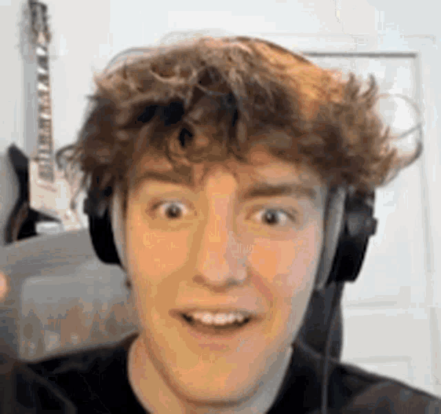 a young man wearing headphones is making a surprised face .