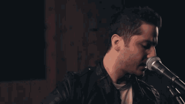 a man singing into a microphone with a dark background