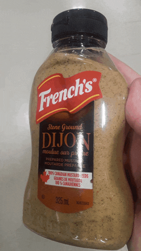 a person is holding a bottle of french 's dijon