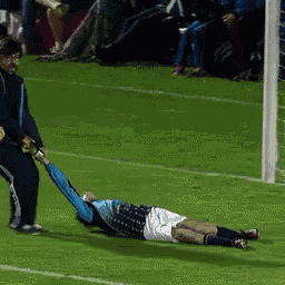 a soccer player is laying on the field while being pulled by another player