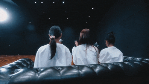 a group of women are sitting on a black couch
