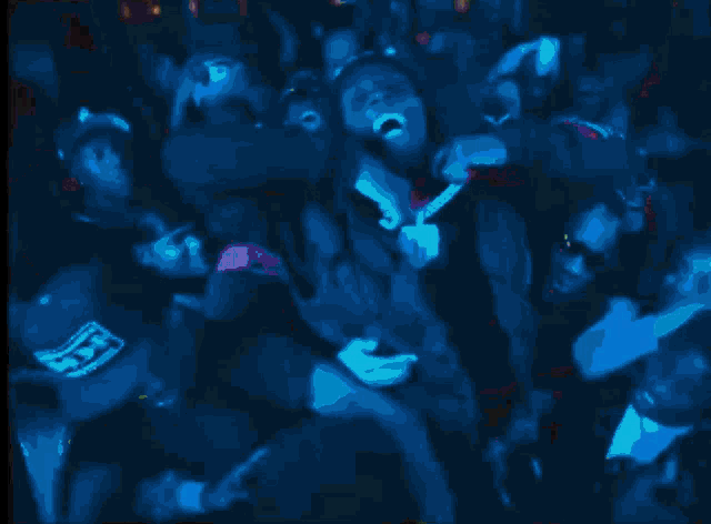 a group of people dancing in a dark room with a blue background