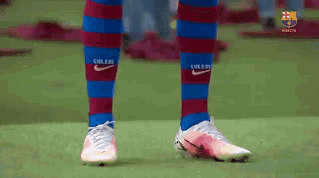 a soccer player wearing a pair of nike socks and a pair of soccer cleats is standing on a field .