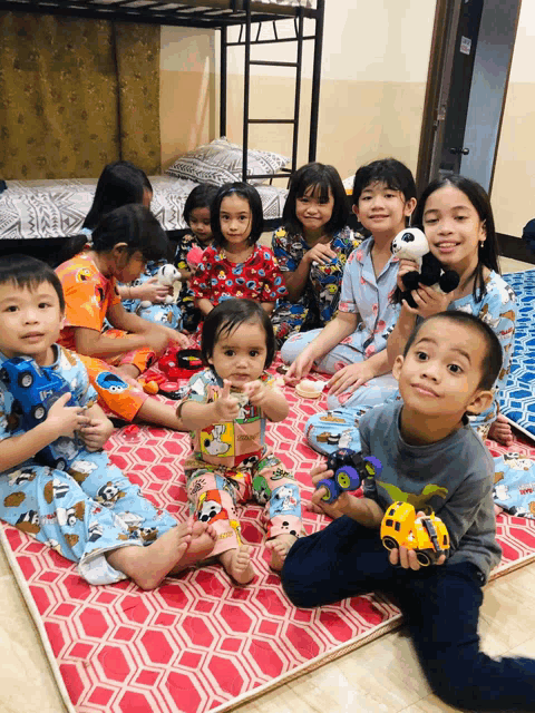 a group of children are sitting on the floor playing with toys and one of them is wearing a shirt that says disney on it