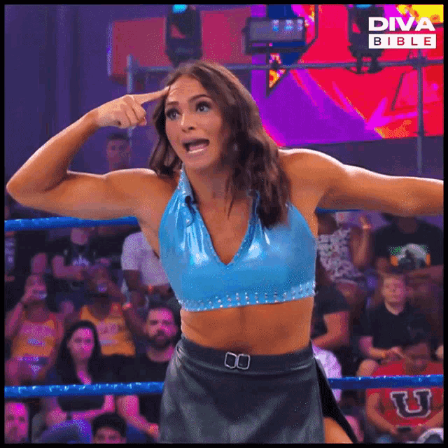 a woman in a blue top and black skirt is standing in a diva bible wrestling ring