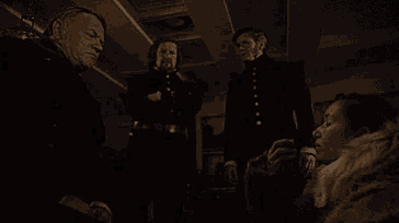 a group of men are standing around a woman in a dark room .