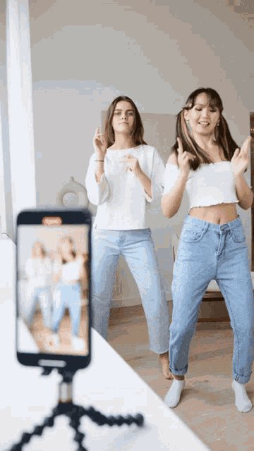 two girls are dancing in front of a phone that says stop on it