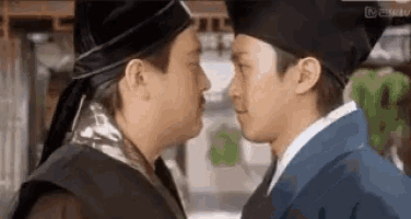 two men are standing next to each other and kissing each other .