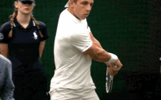 a man in a white shirt is holding a tennis racquet on a court