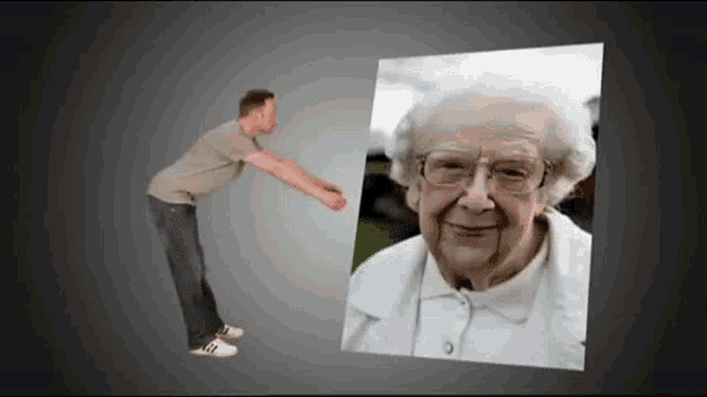 a man is standing next to a picture of an elderly woman with glasses