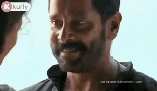 a man with a beard and mustache is smiling while looking at a woman .