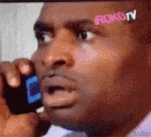 a man is talking on a cell phone and has a roku tv sticker on his forehead