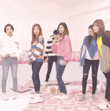 a group of women are standing next to each other in a room with a pink rug .