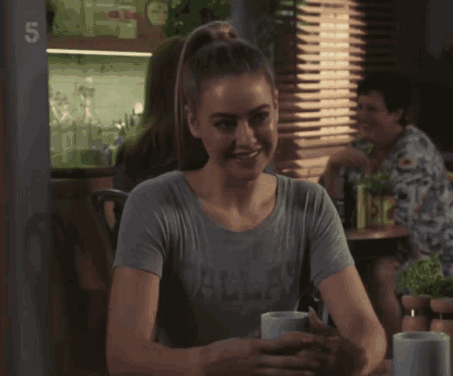 a woman in a dallas shirt sits at a table with two cups of coffee