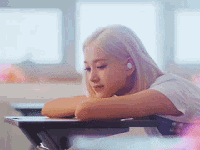 a woman is sitting at a desk with her head on her arm .