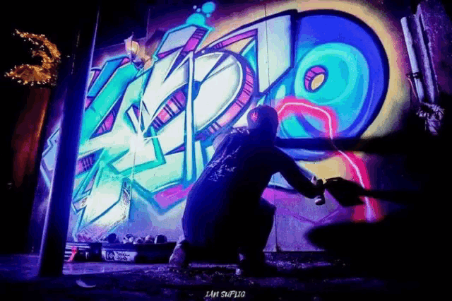 a man is spray painting graffiti on a wall with the letters kzd on it