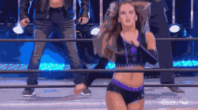 a woman in a black and purple outfit is standing in a ring
