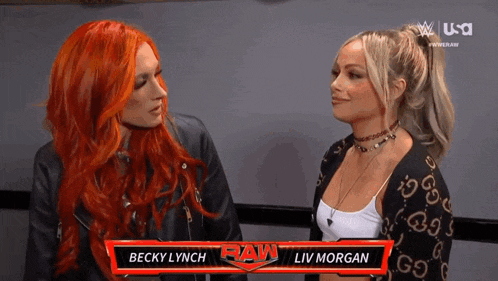 two women with red hair are sitting next to each other in front of a banner that says raw .