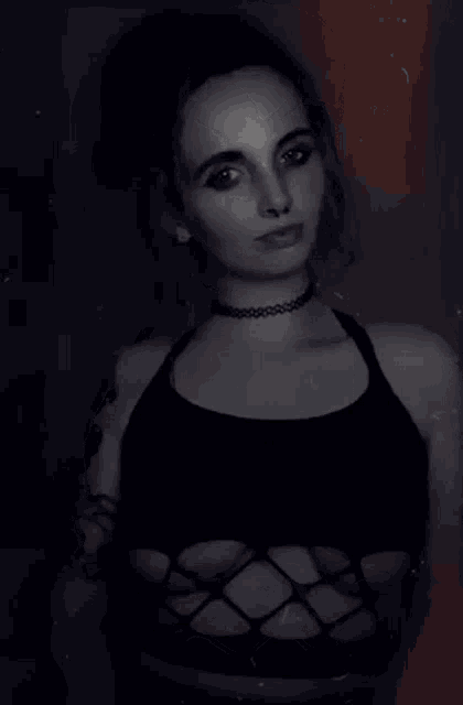 a woman wearing a choker and a black top is sticking out her tongue