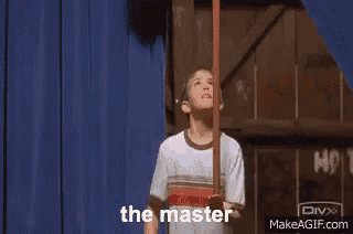 a group of people are sitting in a room and a man is standing in front of them with the words the master written on it .