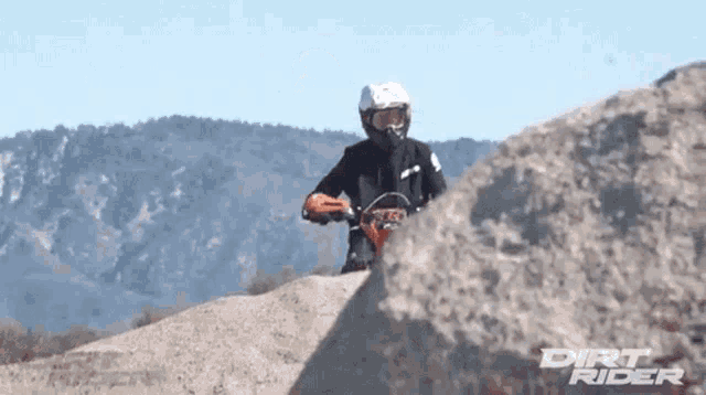 a dirt rider is riding a motorcycle on a rocky hillside